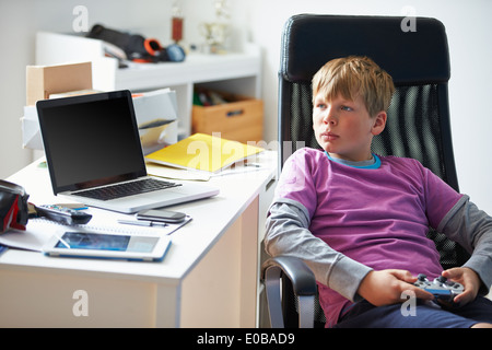 Ragazzo la riproduzione del video gioco in camera da letto Foto Stock