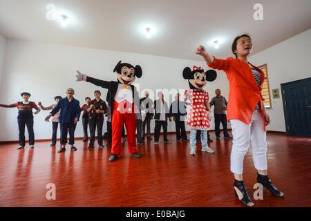 Tongxiang, cinese della Provincia di Zhejiang. 8 Maggio, 2014. Senior la gente impara la figura di danza con membri del personale di alta classe servizio comunitario centro per gli anziani nel villaggio di Yongle di Tongxiang City, est della Cina di Provincia dello Zhejiang, 8 maggio 2014. Una di alta classe RSA è messo in uso qui il giovedì, che andrà a beneficio di senoirs tra i residenti locali e dei lavoratori migranti. © Xu Yu/Xinhua/Alamy Live News Foto Stock