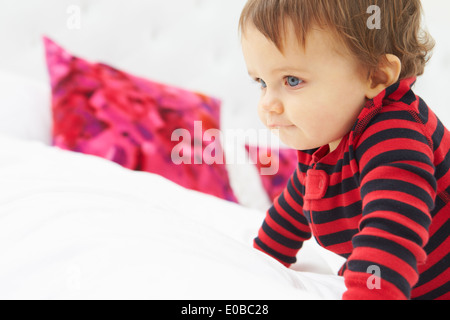 Bimbo gattona sul letto indossando pigiami Foto Stock