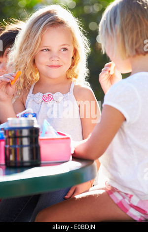Gli alunni elementari seduta a tavola a mangiare il pranzo Foto Stock
