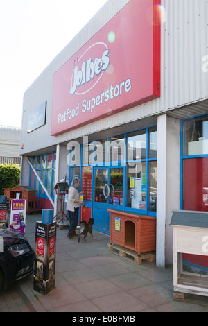 Il cliente con il cane di entrare Jollyes Superstore di produzione di alimenti per animali da compagnia. Foto Stock