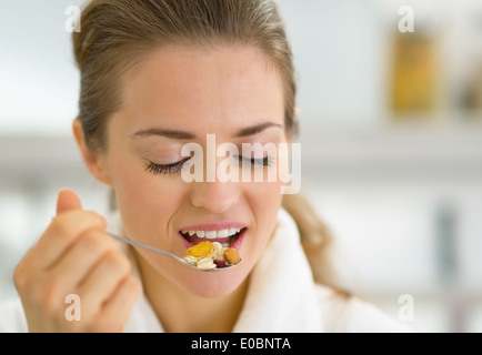 Ritratto di giovane donna mangiare muesli in cucina Foto Stock