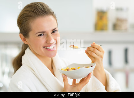 Felice giovane donna mangiare muesli in cucina Foto Stock