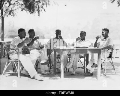 Questa foto mostra i giocatori di cricket che si fermano durante una partita sotto i cieli di fine estate. L'immagine cattura l'atmosfera rilassata di una partita di cricket e l'aspetto sociale dello sport. Foto Stock