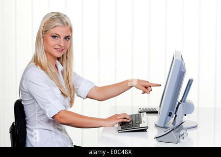 Giovane donna con il computer in ufficio. Prima di sfondo luminoso, Junge Frau mit Computer im Buero. Vor hellem Hintergrund Foto Stock
