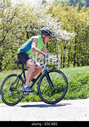 Boss allenatori fitness e rigidi bicicletta su una ruota da corsa, Senior Fitness trainiert und faehrt Fahrrad auf einem Rennrad Foto Stock