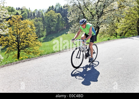 Boss allenatori fitness e rigidi bicicletta su una ruota da corsa, Senior Fitness trainiert und faehrt Fahrrad auf einem Rennrad Foto Stock