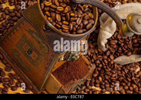 Molti i chicchi di caffè si trovano accanto a un macinino da caffè. Caffè macinato fresco, Viele Kaffeebohnen liegen neben einer Kaffeemuehle. Frisch g Foto Stock