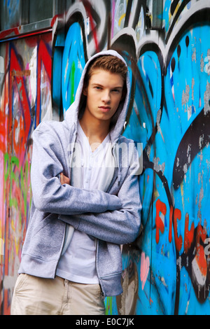 Un fresco guardando giovane uomo prima di graffiti, Ein cool blickender Jugendlicher Mann vor Graffiti Foto Stock