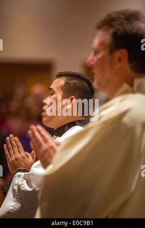 L'americano asiatico vice parroco di San Timoteo della Chiesa Cattolica, Laguna Niguel, CA, la preghiera durante la messa. Nota vesti. Foto Stock