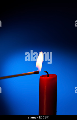 Una candela rossa è illuminato con un match., Eine rote Kerze wird Mit einem Streichholz angezuendet. Foto Stock