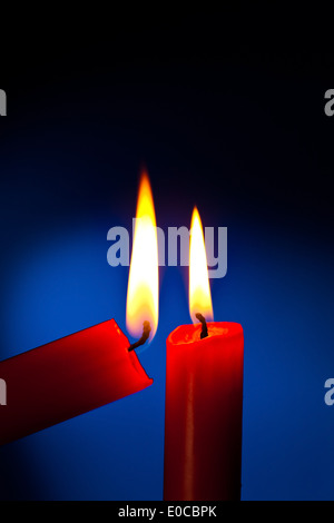 Una candela rossa è illuminato con un match., Eine rote Kerze wird Mit einem Streichholz angezuendet. Foto Stock