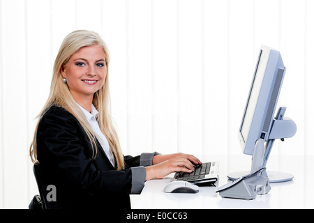 Giovane donna si siede davanti a un computer in ufficio., Junge Frau sitzt vor einem Computer Buero im. Foto Stock