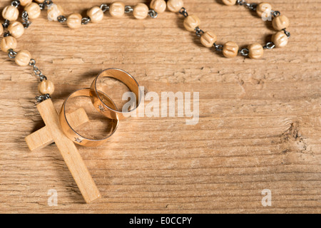 Weding anelli e rosario sulla vecchia scrivania in legno Foto Stock