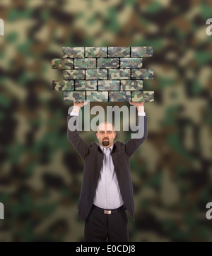 Imprenditore tenendo un grande pezzo di un muro di mattoni camouflage pattern isolato Foto Stock