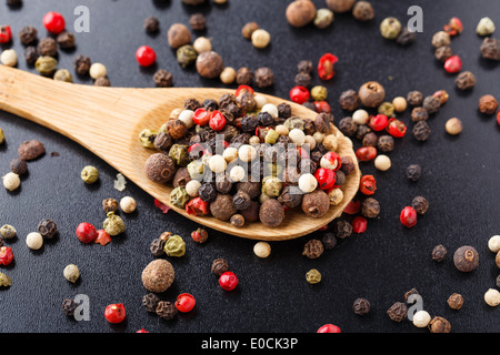 Peperoni misti su un cucchiaio di legno Foto Stock