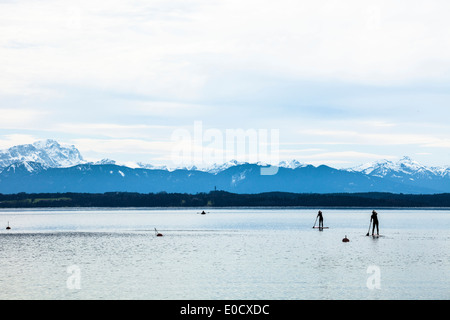 Stand-up-canoisti sul Lago di Starnberg in aprile e si affaccia sulle Alpi e il massiccio dello Zugspitze, Fuenfseenland, Wettersteingebirge, Alpi bavaresi Foto Stock