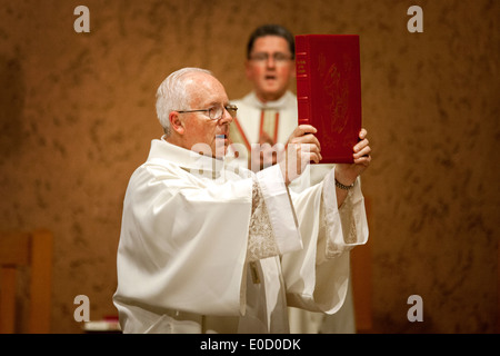 Un anziano diacono tiene il Vangelo durante la grande Veglia pasquale a San Timoteo della Chiesa Cattolica, Laguna Niguel, CA. Nota pastore in background. Foto Stock