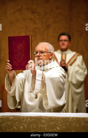 Un anziano diacono tiene il Vangelo durante la grande Veglia pasquale a San Timoteo della Chiesa Cattolica, Laguna Niguel, CA. Nota pastore in background. Foto Stock