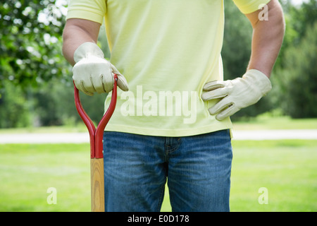 Uomo con utensile da giardinaggio in piedi nel cortile posteriore Foto Stock