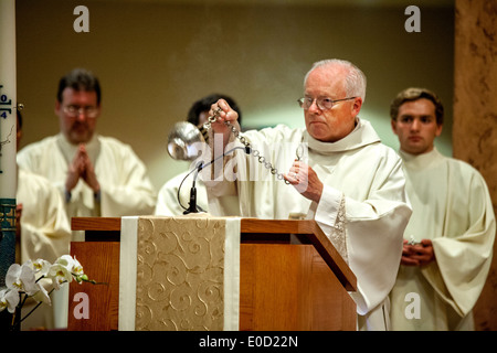 Un anziano diacono onde un incensiere (bruciatore di incenso) durante la grande Veglia pasquale a San Timoteo della Chiesa Cattolica, Laguna Niguel, CA. Nota i chierichetti in background. Foto Stock