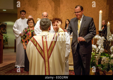 Il parroco di San Timoteo della Chiesa Cattolica, Laguna Niguel, CA, benedice i nuovi membri della congregazione la notte del loro battesimo. Nota vesti bianche e sponsor a destra. Foto Stock