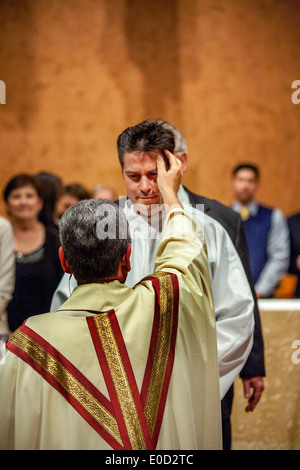 Il parroco di San Timoteo della Chiesa Cattolica, Laguna Niguel, CA, benedice un nuovo membro della congregazione la notte del suo battesimo. Nota tunica bianca. Foto Stock