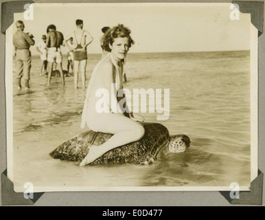 Giovane donna a cavallo sul dorso di una tartaruga alla spiaggia di Mon Repos Foto Stock