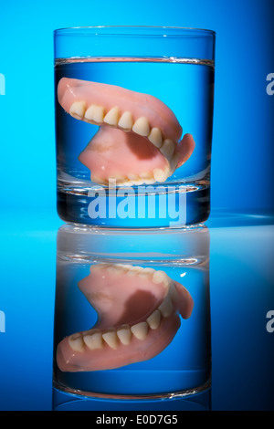 Una serie di protesi viene pulita in un bicchiere con acqua. Diritto igiene., Ein Zahnersatz wird in einem Glas mit Wasser gereinigt. Ricca Foto Stock