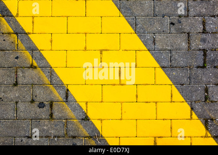 Un giallo linea diagonale dipinta sul marciapiede di un parcheggio Foto Stock