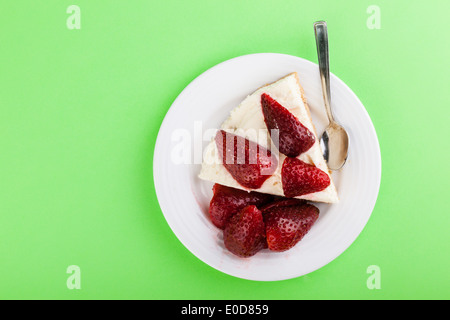 Una deliziosa crema pasticcera torta con le fragole su una piastra bianca su sfondo verde Foto Stock