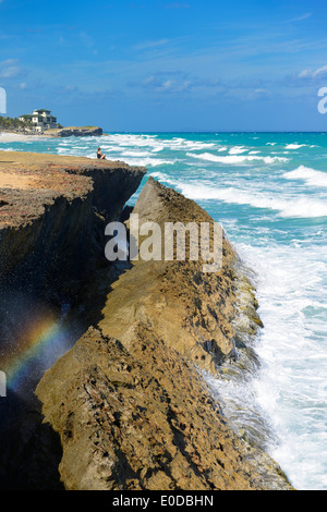 Donna meditando su roccia lavica shore a Varadero Beach resort Cuba nel vento ad alta sull'Oceano Atlantico Foto Stock