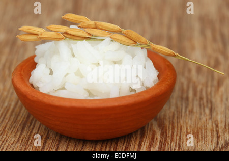 Paddy semi con riso bollito su una superficie di legno Foto Stock