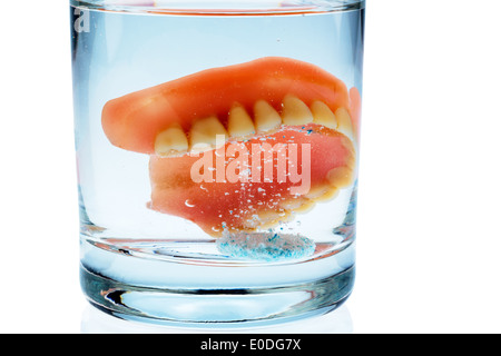 Una serie di protesi viene pulita in un bicchiere con acqua. Diritto igiene., Ein Zahnersatz wird in einem Glas mit Wasser gereinigt. Ricca Foto Stock