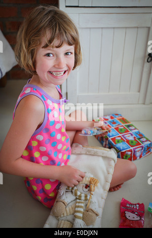 Un felice sorridente ragazza apertura presenta il giorno di Natale Foto Stock