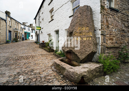 L'Adam Sedgwick monumento,nella strada principale lastricata in pietra, il villaggio di ammaccatura, Cumbria, Regno Unito. Foto Stock