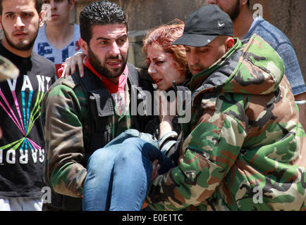 Homs, sabato. Il 10 maggio, 2014. Trasferimenti di persone una donna, che è stato ferito da una mina che è andato via in m Bustan Al-Diwan quartiere nella parte vecchia della città di Homs, Siria, Sabato 10 Maggio, 2014. Secondo i resoconti dei mass media, tre persone sono state ferite dal blast. Il governatore della Siria La provincia centrale di Homs Talal Barazi venerdì ha dichiarato la città vecchia di Homs sicuro e svuotare di armi e ribelli armati, dopo l'evacuazione dell'ultimo lotto di ribelli vi, il funzionario SANA News Agency. Credito: Bassem Tellawi/Xinhua/Alamy Live News Foto Stock