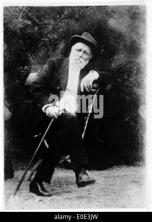 Un ritratto in bianco e nero di un anziano seduto all'aperto. Questa immagine cattura la tranquilla contemplazione del soggetto, incorniciato in uno stile vintage senza tempo tipico della fotografia dei primi anni del XX secolo. Foto Stock