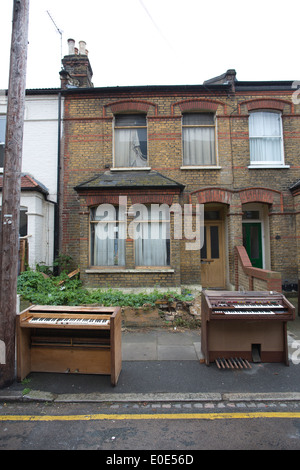 Organi musicali flytipped al di fuori di una corsa verso il basso casa a schiera a Londra, Inghilterra, Regno Unito Foto Stock