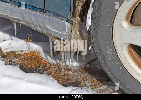 Una vettura con ghiaccioli appesi da essa inizia un disgelo invernale Foto Stock