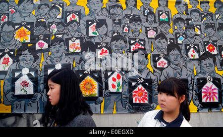 Ansan, Corea del Sud. Il 10 maggio 2014. Gli studenti a piedi passato appeso un quadro raffigurante le vittime del traghetto Sewol e loro familiari mentre i partecipanti erano in possesso di un rally contro ciò che esse insistono, lax risposta del Presidente Parco-geun hye il governo dopo il traghetto Sewol è stata affondata nelle acque al largo del sud-ovest di isola Jindo on April 16, 2014, a plaza, Ansan, Corea del Sud, di sabato 10 maggio, 2014. Circa 13.000 persone hanno partecipato al rally per chiedere le dimissioni del Presidente Parco e di cordoglio per le vittime della tragedia, secondo i media locali. Foto Stock