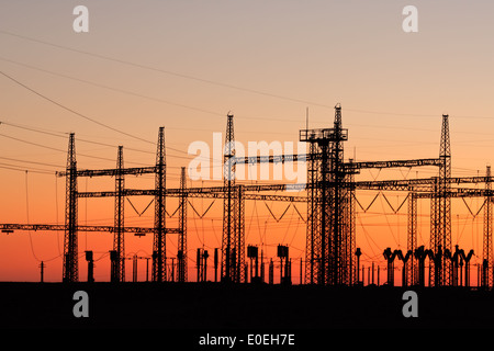 Stagliano tralicci elettrici contro un cielo rosso al tramonto Foto Stock