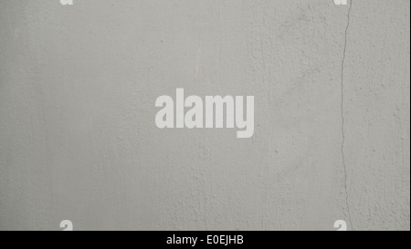 Questa superficie della parete in cemento testurizzato è caratterizzata da un sottile colore bianco sporco con una spaccatura sottile che aggiunge carattere. Foto Stock