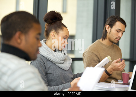 Giovane africano donna americana leggere le note con i compagni di classe lo studio intorno nella biblioteca universitaria. Studenti in preparazione per l'esame. Foto Stock