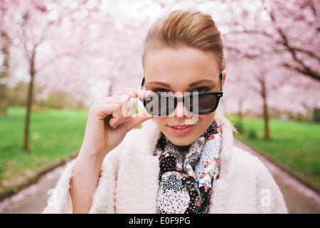 Chiudere l immagine della giovane e bella donna che guarda la fotocamera. Giovani caucasici modello femmina cerca attraverso occhiali da sole. Foto Stock