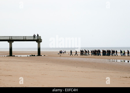 La spiaggia di Omaha, in Normandia, Francia. Il vecchio molo presso la spiaggia di Omaha con la bassa marea. Mostra un esercito francese gruppo a piedi vicino al molo. Foto Stock