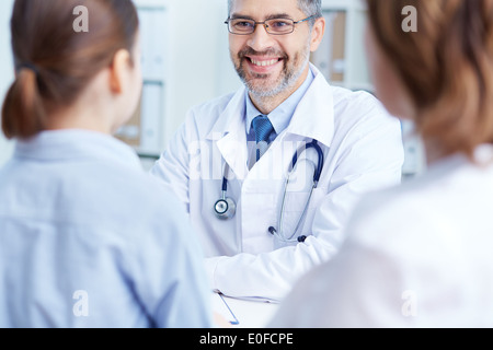 Fiducioso praticante parlando a pazienti in ospedale Foto Stock