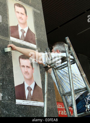 Damasco, Siria. Il 12 maggio 2014. Un lavoratore mette l elezione dei manifesti in Damasco, Siria, 12 maggio 2014. Un giorno prima, il paese della suprema Corte costituzionale ha dato i candidati presidenziali, Maher Hajjar, Hassan Nouri e attuale Presidente Bashar al-Assad il nullaosta per iniziare la campagna di domenica fino al 2 giugno con un giorno di anticipo del 3 giugno le elezioni. Credito: Bassem Tellawi/Xinhua/Alamy Live News Foto Stock