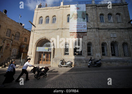 Gerusalemme, Gerusalemme, Territorio palestinese. Il 12 maggio 2014. Ultra ebrei ortodossi a piedi passato un grande poster del Papa Francesco a Christian Information Center nella città vecchia di Gerusalemme, 12 maggio 2014. Più di 200 ebrei ortodossi hanno protestato lunedì contro il papa la prevista visita al sito dove i cristiani credono Gesù Cristo ha avuto la sua Ultima Cena © Saeed Qaq APA/images/ZUMAPRESS.com/Alamy Live News Foto Stock