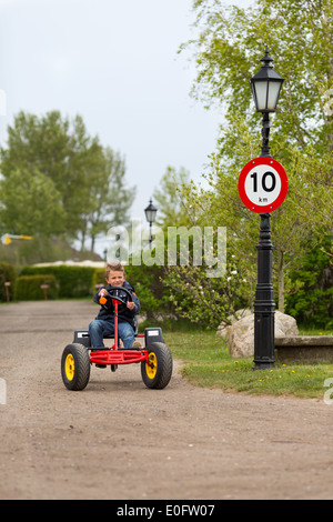 Ragazzo del pedale di guida carrello vai avanti a 10 MPH segnale di limite di velocità. I marchi sono stati rimossi. Foto Stock